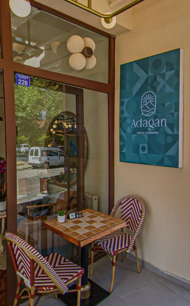 Adagan Kafe’nin giriş kapısı ve dış cephe tabelası, önünde zarif sandalyelerle birlikte